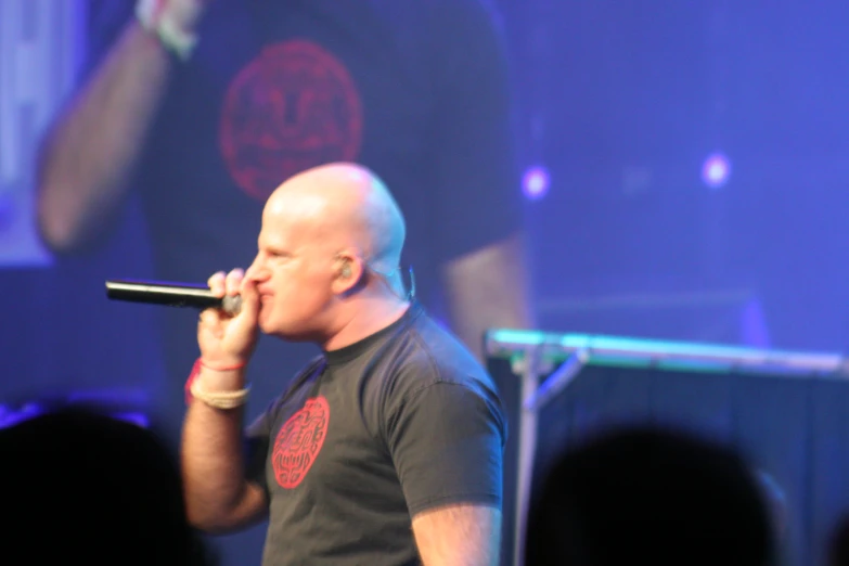 a man wearing a black shirt sings into a microphone