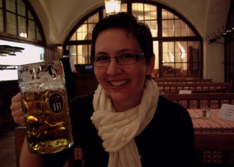 the woman is holding up a large glass of beer