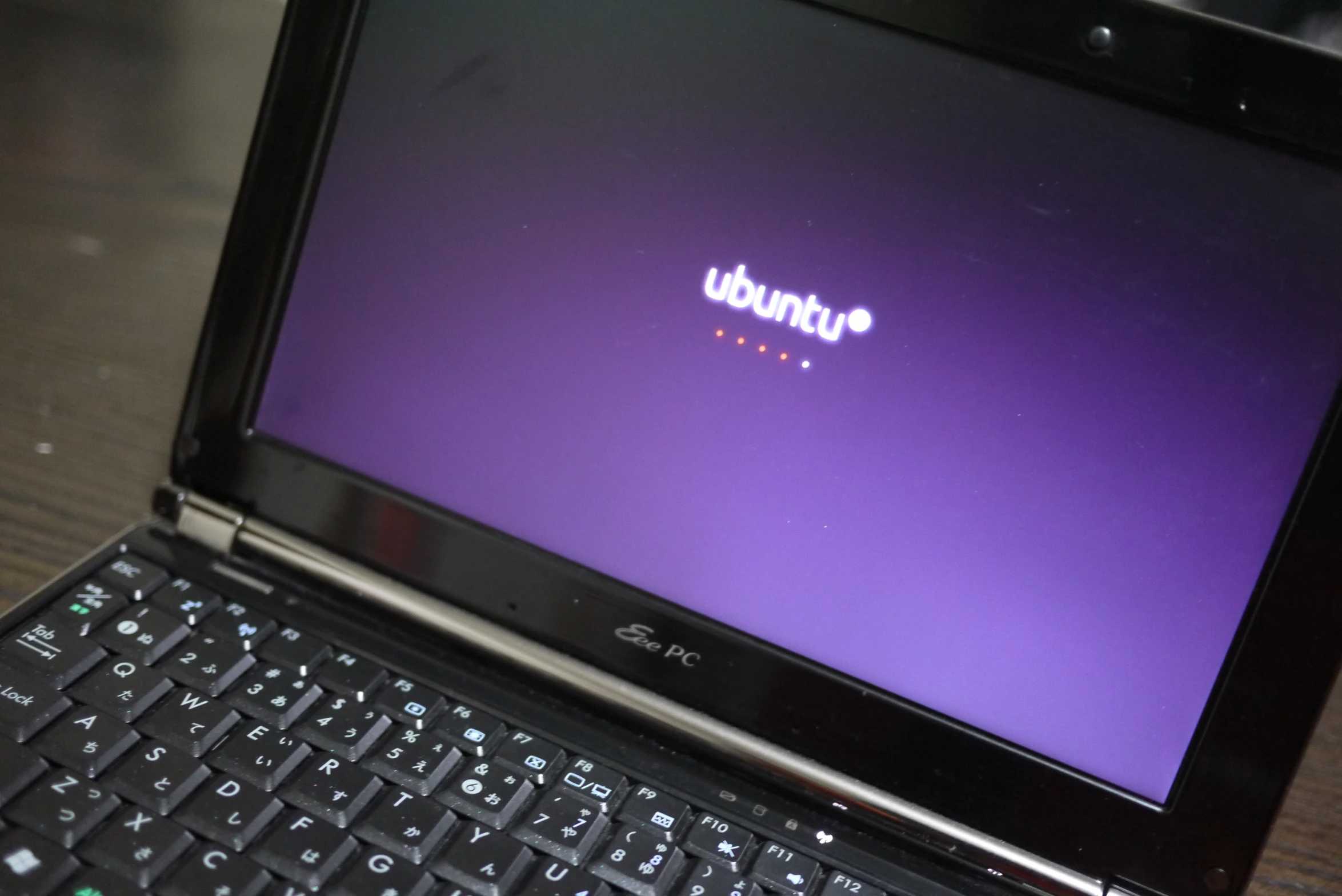 a black laptop sitting on a table with a purple screen