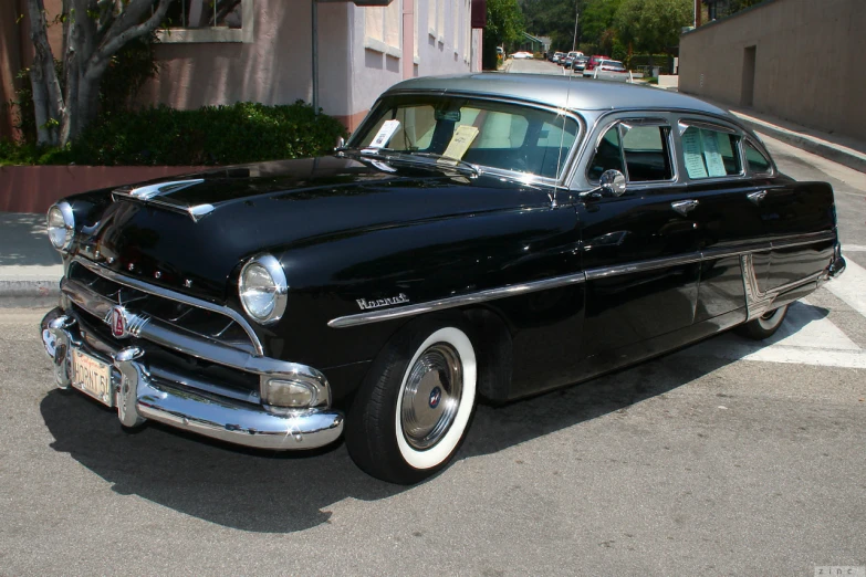 a classic car sits parked on the side of the street