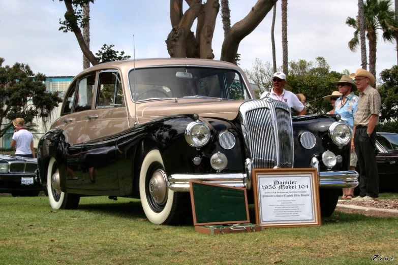 an old fashion car is shown with two people near by