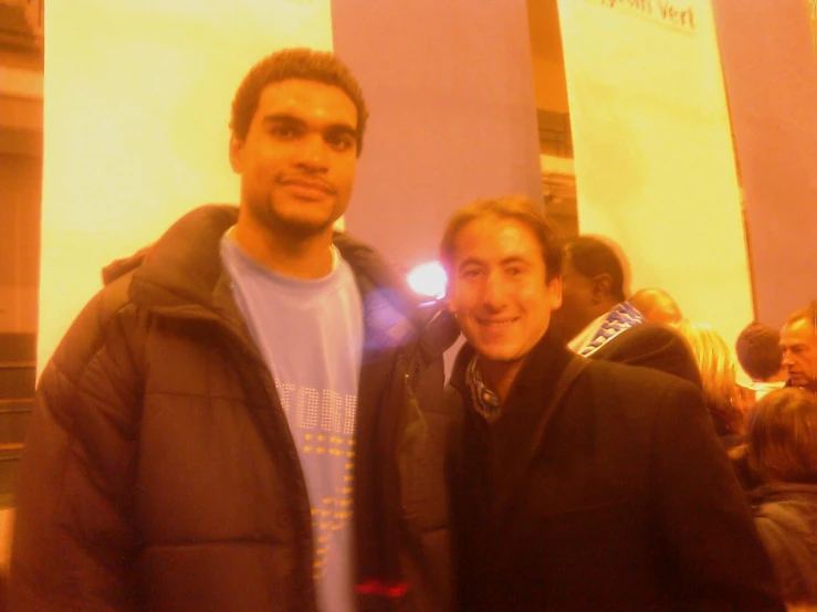 two young men are posing for a picture in a crowd