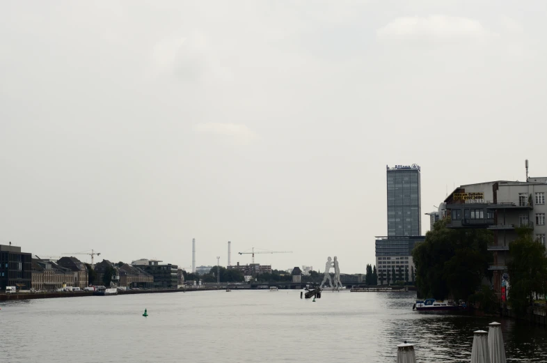 boats sailing along the shore near buildings on a cloudy day