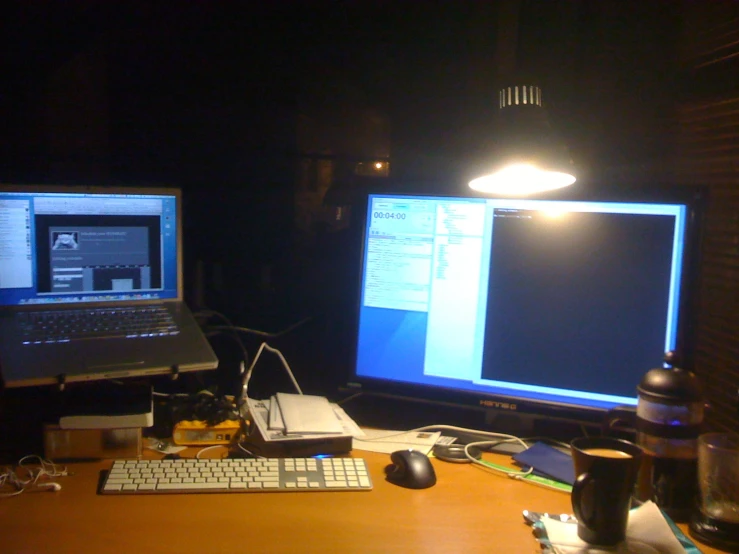 two computer screens sit next to a lamp and desk