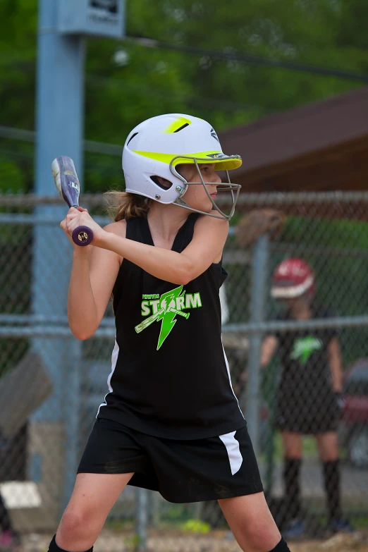 young woman wearing black uniform holding a baseball bat