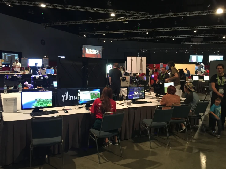 a group of people standing around tables using computers