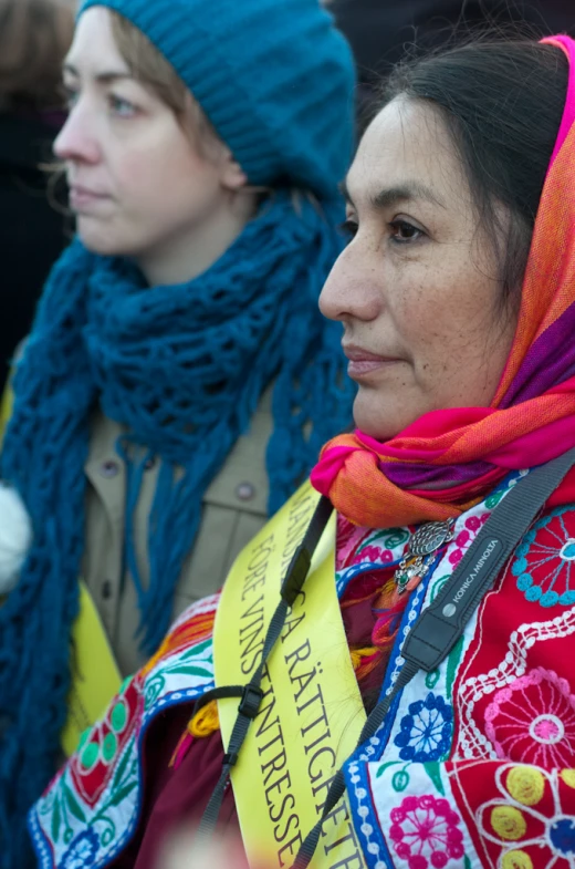 a woman in traditional dress looks on while wearing a scarf and hat