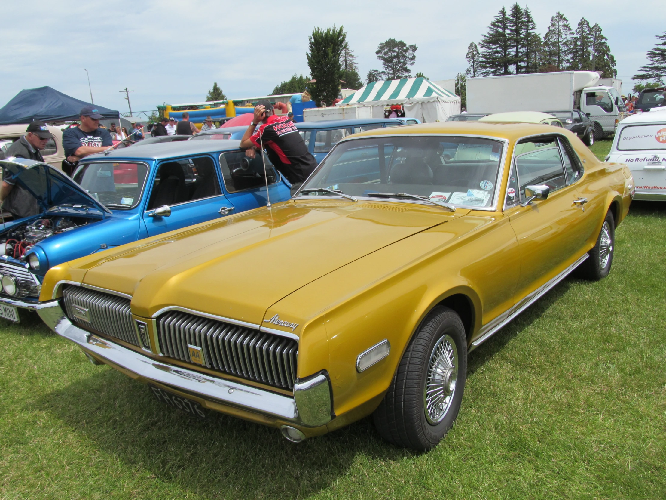 a gold car parked next to another blue car on top of grass