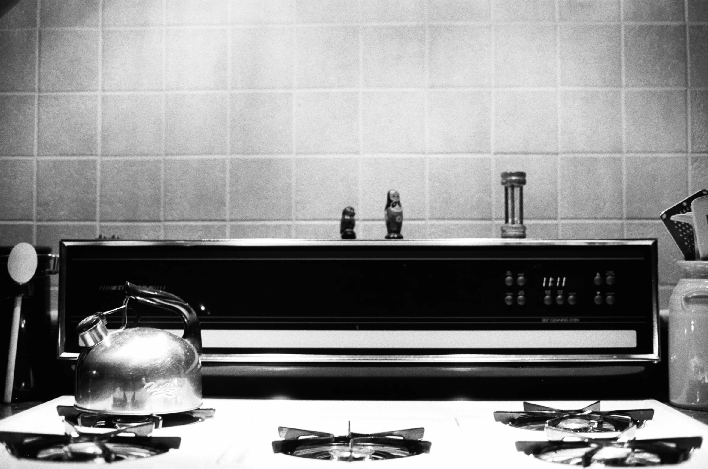 a kettle sits on a stove, beside some toaster oven