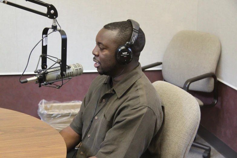 a man in headphones sits in front of a microphone and computer