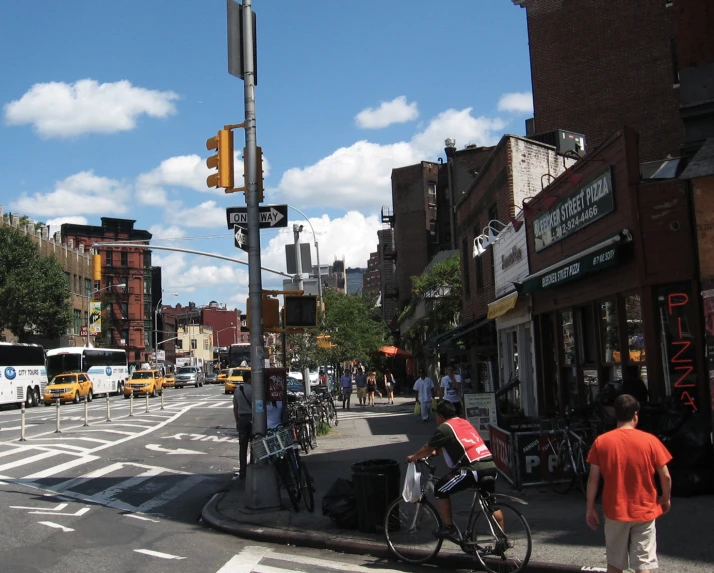 people walk down a busy street near traffic lights