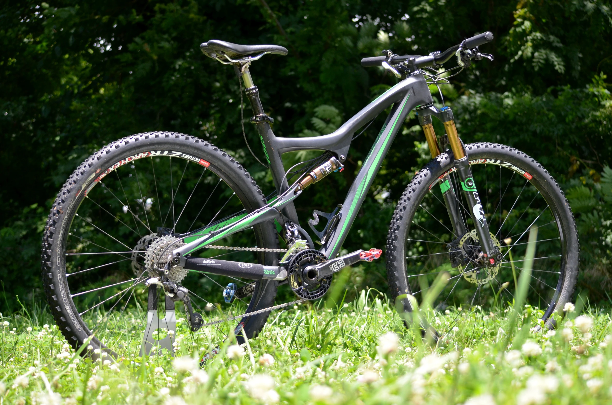 the bike is resting in the grass next to the forest