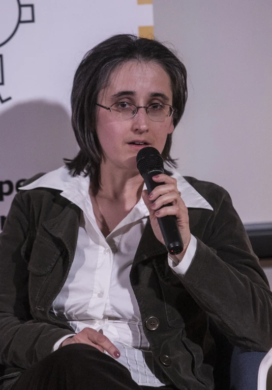 a woman in glasses is holding a microphone