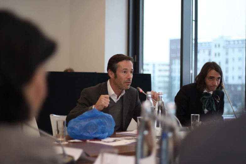 a man sitting at a table talking to people