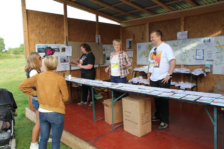 several people standing near boxes on the ground and around a table with many papers