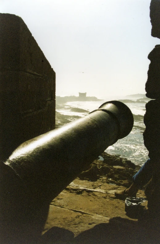 an old cannon is at the edge of a wall by the ocean