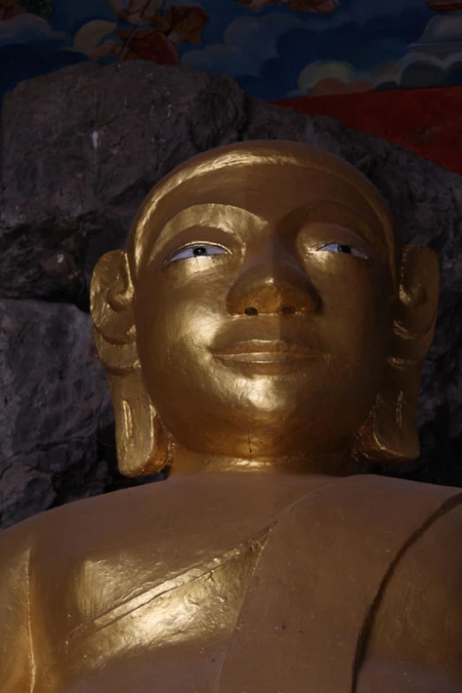 a golden statue in front of a stone wall