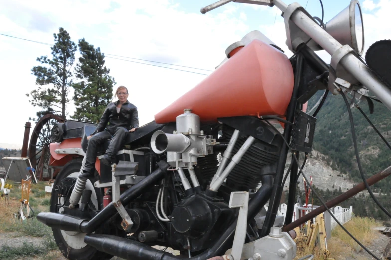 a girl sitting on the back of a black and red motorcycle