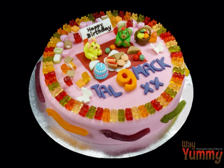 a pink birthday cake is covered with candies