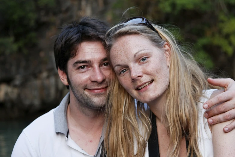 a man and woman hugging next to the water