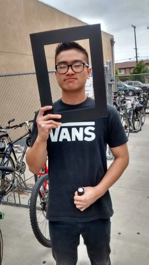 a man wearing glasses holding up a black frame with a po