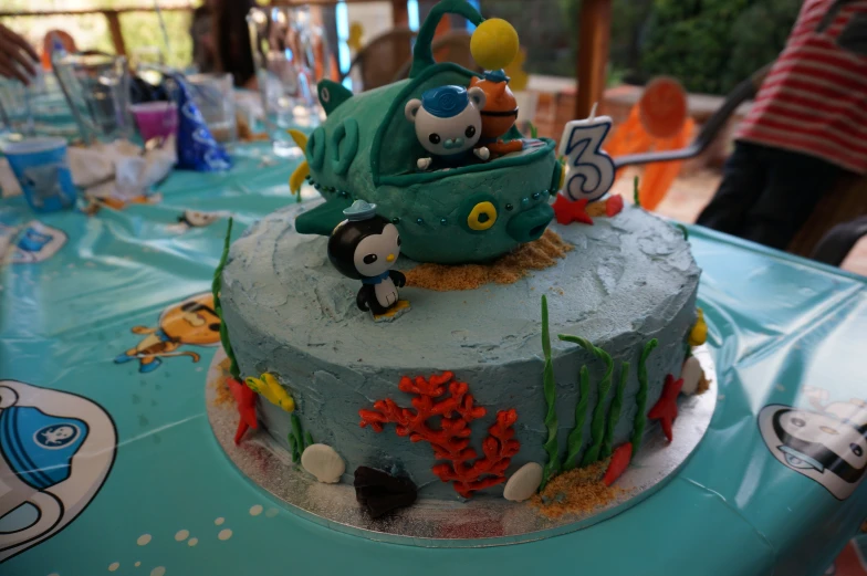 the cake is decorated with blue frosting and features pirate characters