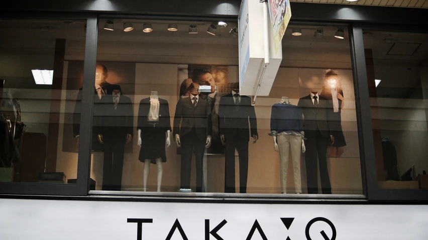 several mannequins dressed in different styles stand inside of a window