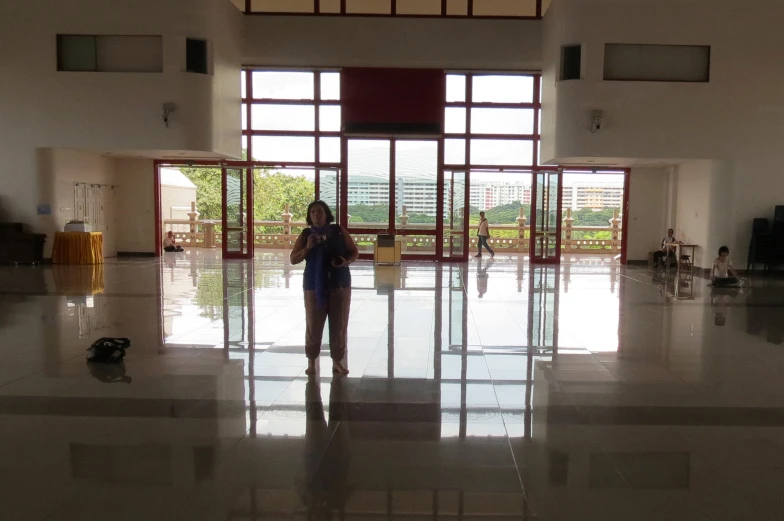 there is a woman standing in a room that has two large windows