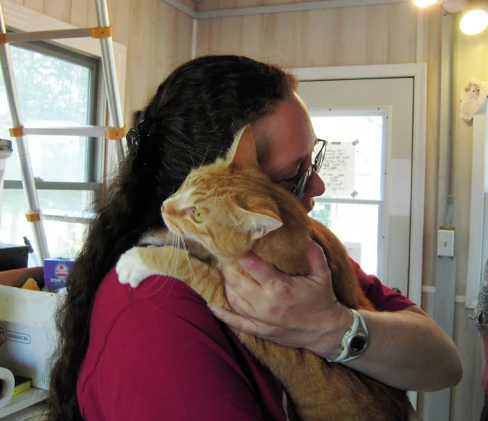 a man that is holding up a cat in his arms