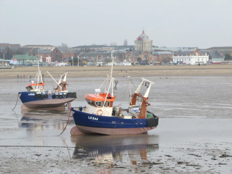 two boats with flags are in the mud at low tide