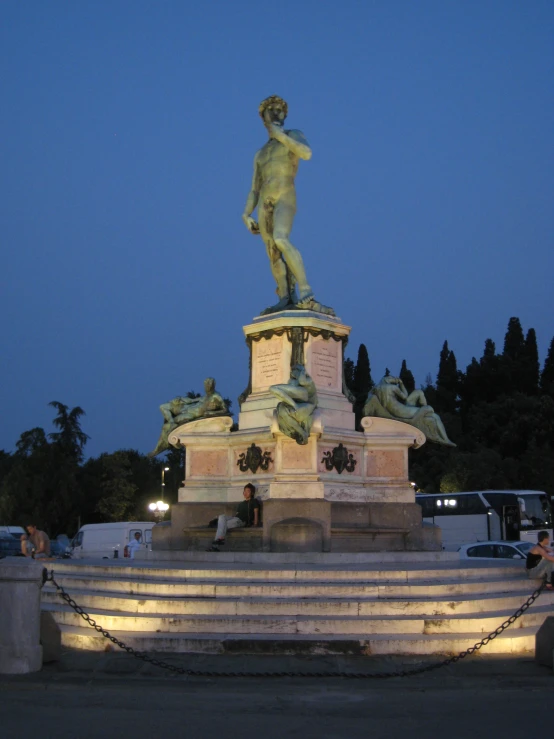 a bronze statue is seen against a dark sky