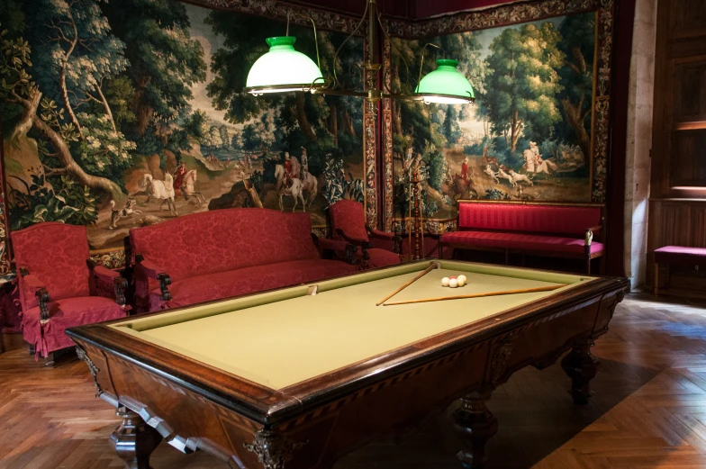 pool table, chair and couch in dark room with painting on wall