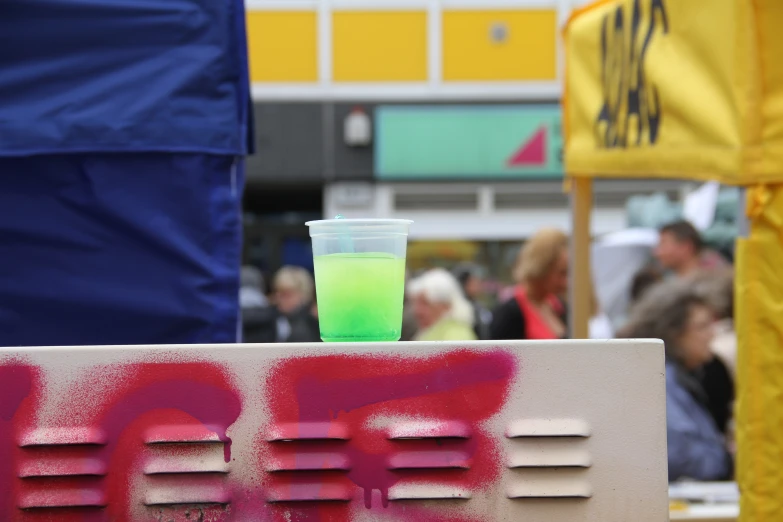 a glass with green liquid sitting on top of a sign