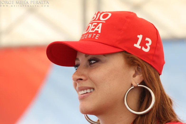 a female with earrings wearing a red hat