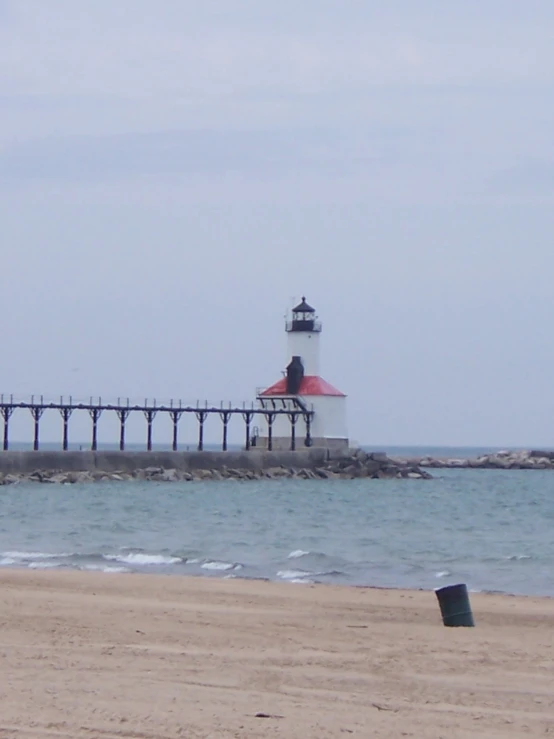 a large lighthouse stands on the shore line near the water