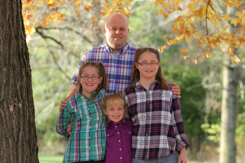 an adult standing between two children in a park