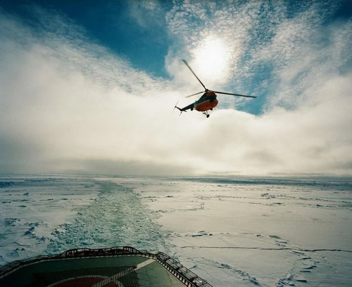 the helicopter flies low over some ice covered water