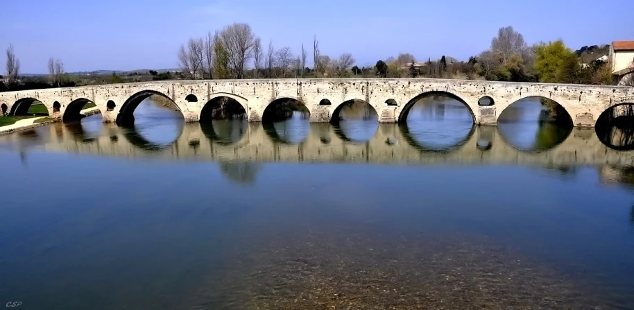 a stone bridge crosses a river surrounded by a small building