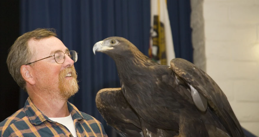 a man standing next to an eagle on his finger