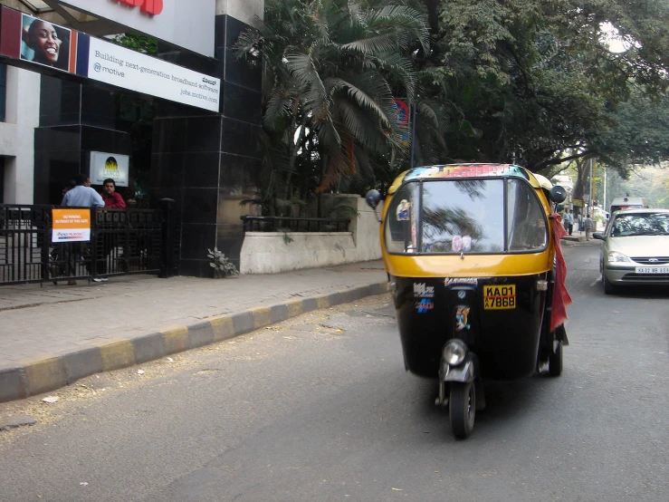 a small yellow and black vehicle is driving down the street