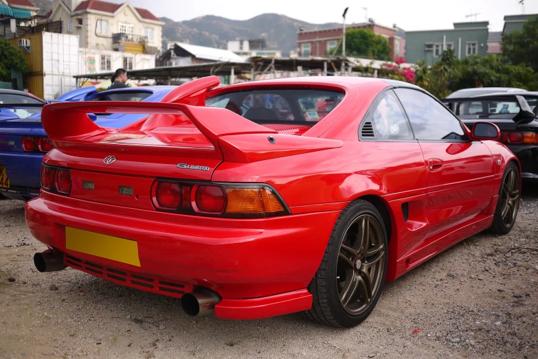 the rear end of a red sports car on a gravel road