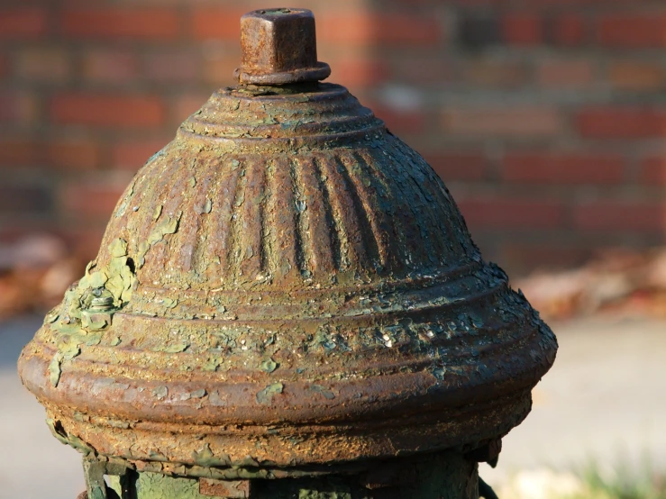 an old rusted fire hydrant near a brick wall