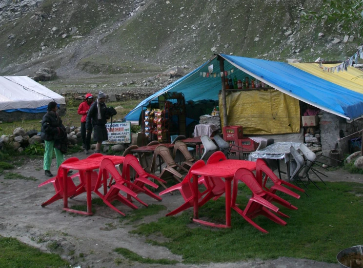 several red chairs on the ground in front of a mountain hut