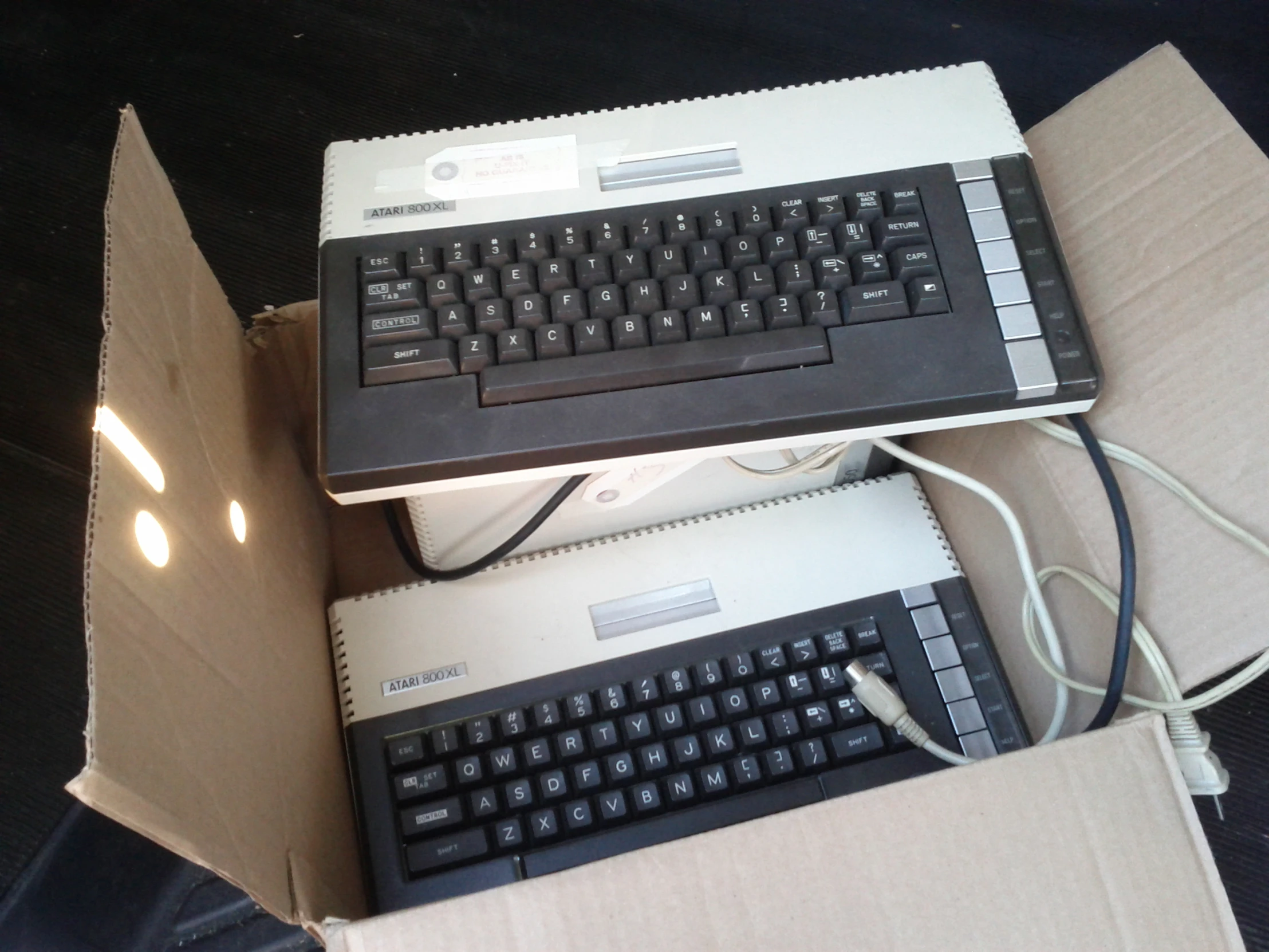 two keyboards and a computer mouse sitting in a cardboard box