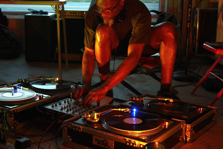 a man bends over an open dj's turntable