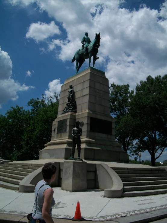 a woman standing in front of a statue of a person riding a horse