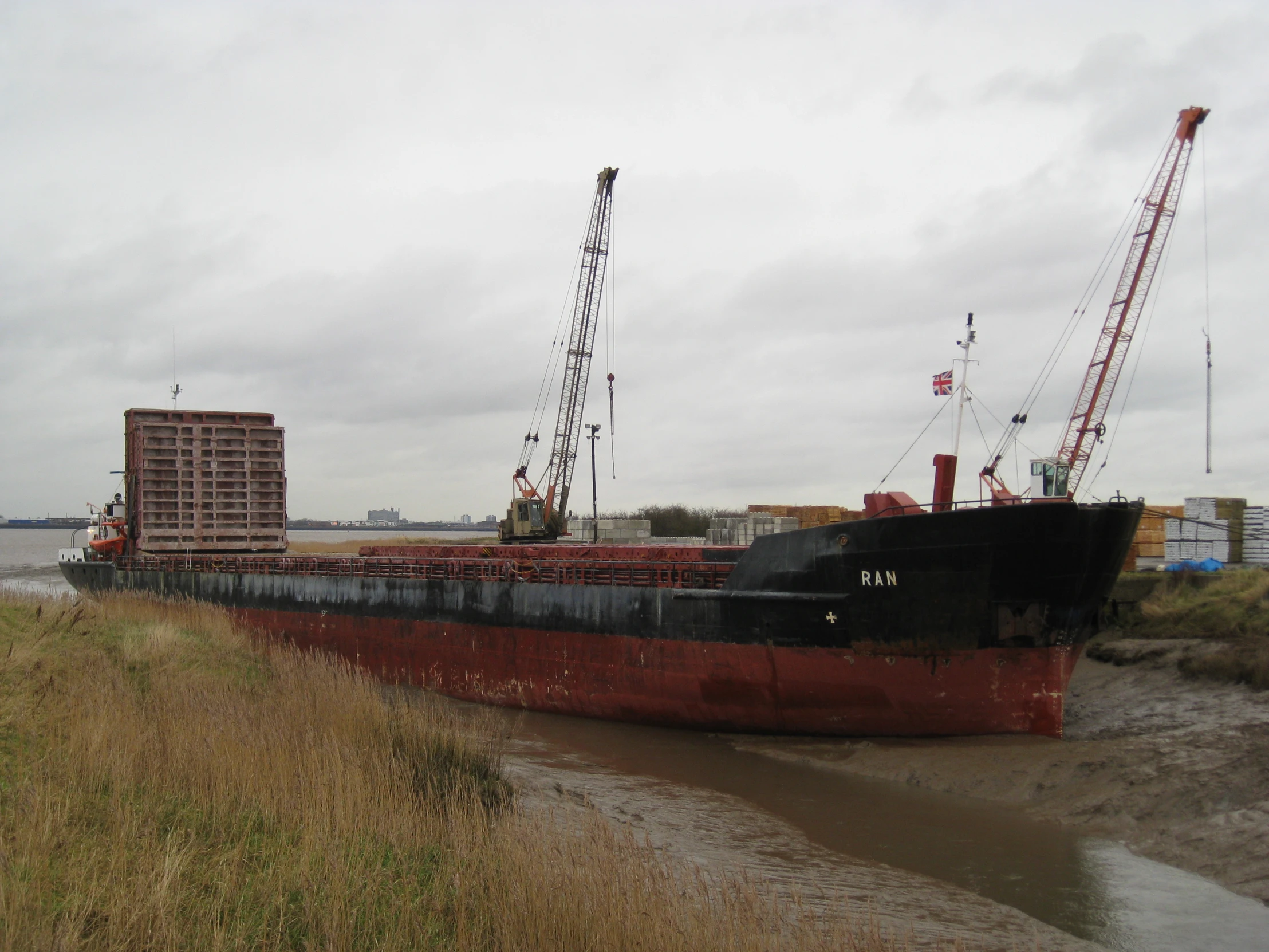 a barge sitting on top of a dry grass covered river bank