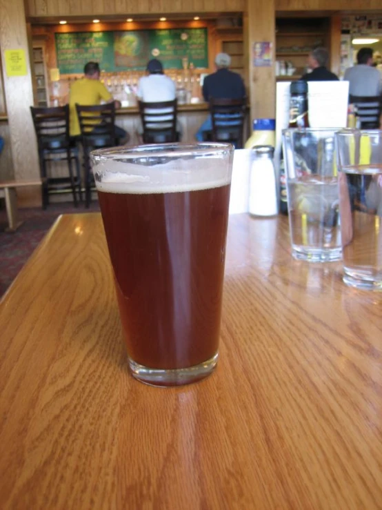 a glass filled with some beer on a wooden table