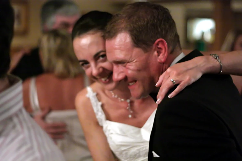 a smiling bride hugging her husband at the wedding