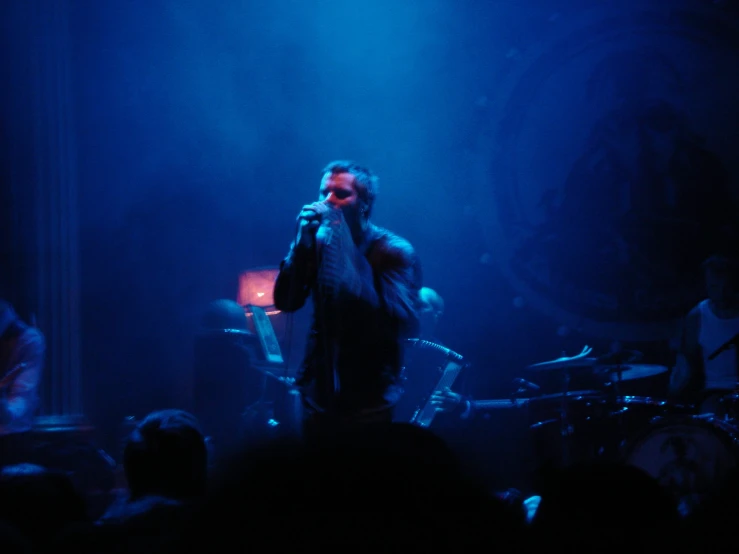 man singing into microphone with band in background